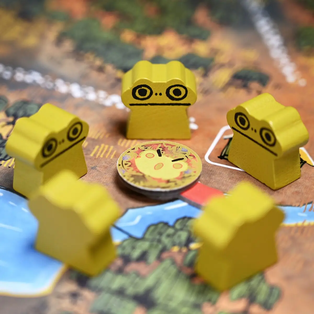 Žluté figurky žab Leknínové diaspory na mapě